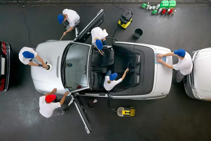 atelier de detailing auto cu mașină pe rampă, echipamente de curățare și lumini puternice pentru inspecție